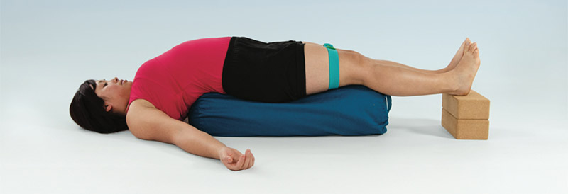 Person demonstrating Setu-Bandha using a round bowser, 2 blocks and a belt